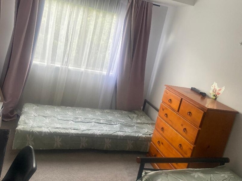 2 single beds with fan, desk, dresser, bookshelf and hanging space