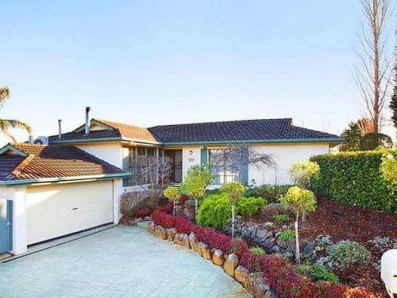 A single-story suburban house features a tiled roof, a prominent double garage with a crea